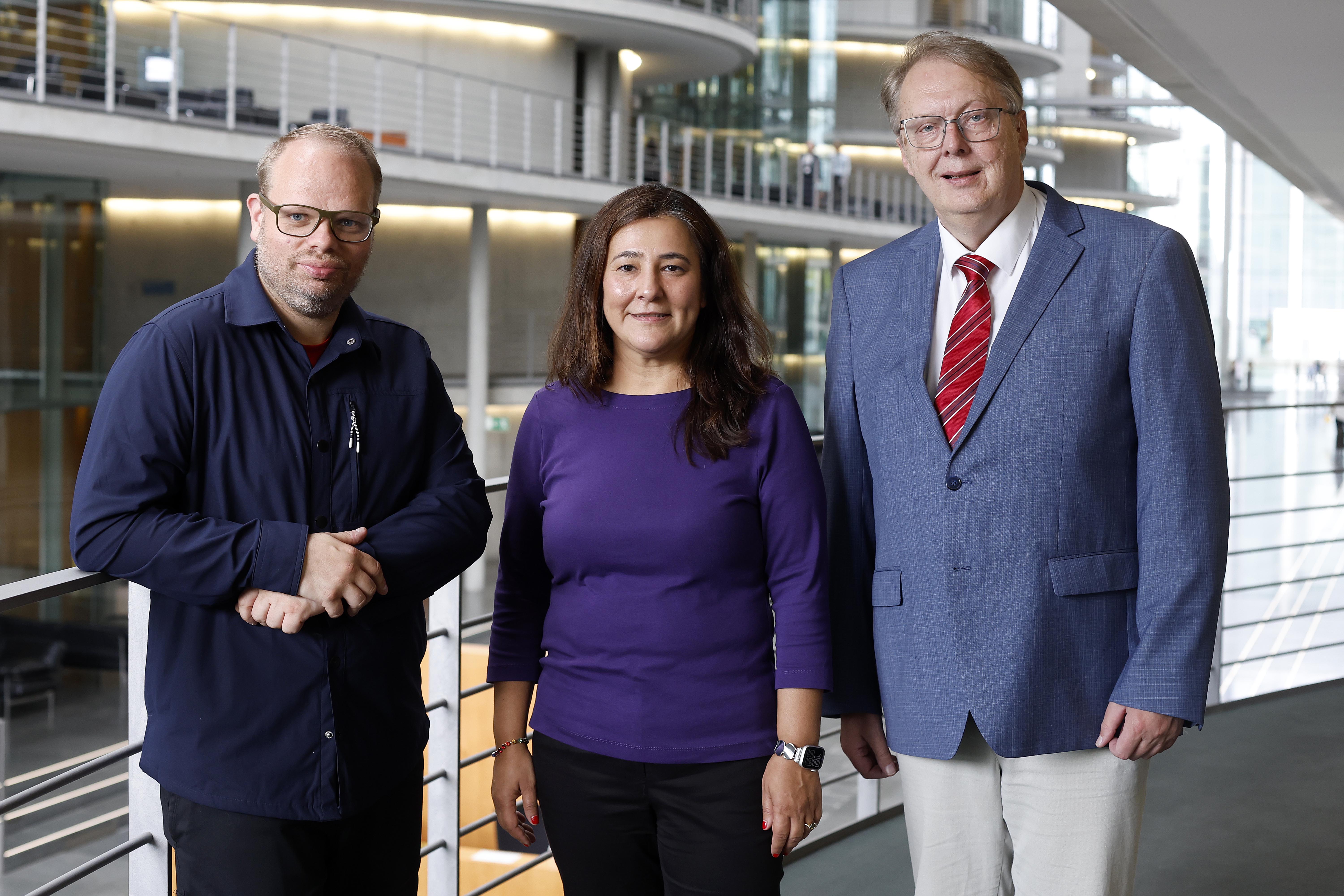 Auf dem Foto sind drei Personen im Bundestagsgebäude zu sehen