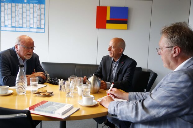 Drei Männer an einem Tisch im Gespräch