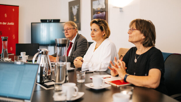 dieses Bild zeigt drei Personen, die an einem Tisch nebeneinander sitzen
