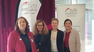 Auf diesem Foto sind 4 Personen vor einer BdB-Beachflag zusehen. 