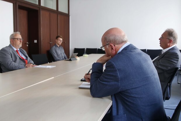 Vier Männer sitzen um einen Tisch herum und reden