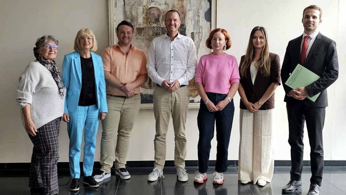 Auf diesem Foto sind sieben Personen zu sehen, die vor einer Wand stehen.