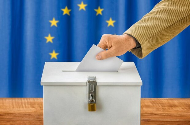 Hand wirft Stimmzettel in Wahlurne