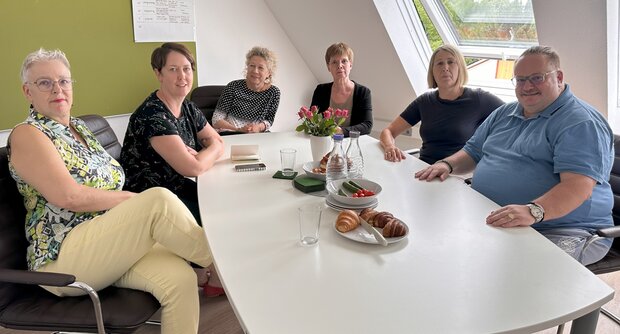 dieses Bild zeigt sechs Personen, die an einem Tisch sitzen
